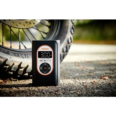 Ein digitaler Reifendruckmesser zeigt '3.00' an und steht vor einem Motorradreifen auf einer Straße.