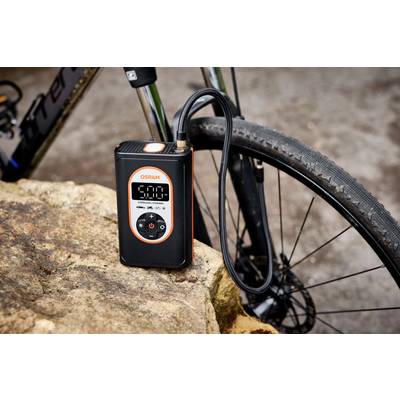 Elektrische Luftpumpe mit digitalem Display an einem Fahrrad auf einem Stein positioniert. Display zeigt '5.0' an.