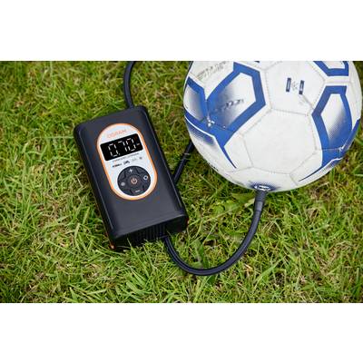 Ein digitaler Luftkompressor pumpt einen Fußball auf. Der Kompressor zeigt '0.28' auf dem Display. Beide liegen auf Gras.