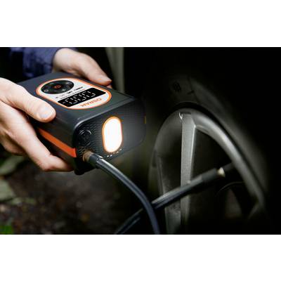 Eine Person pumpt mit einem tragbaren Kompressor die Reifen eines Autos auf. Der Kompressor zeigt eine Druckanzeige.