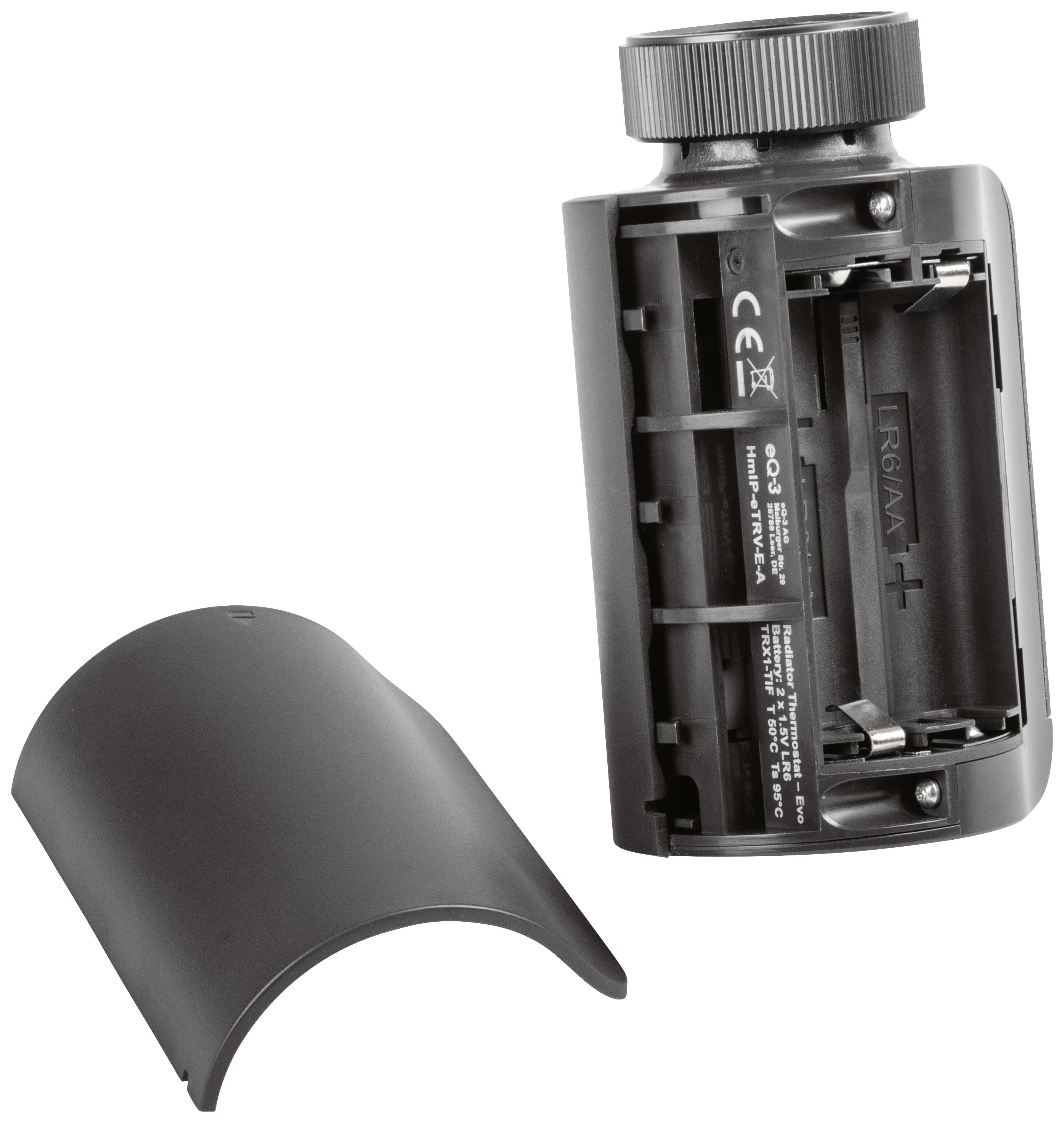 Das Bild zeigt die Rückseite einer elektronischen Kamera mit geöffnetem Batteriefach. Eine abnehmbare Abdeckung ist daneben platziert.