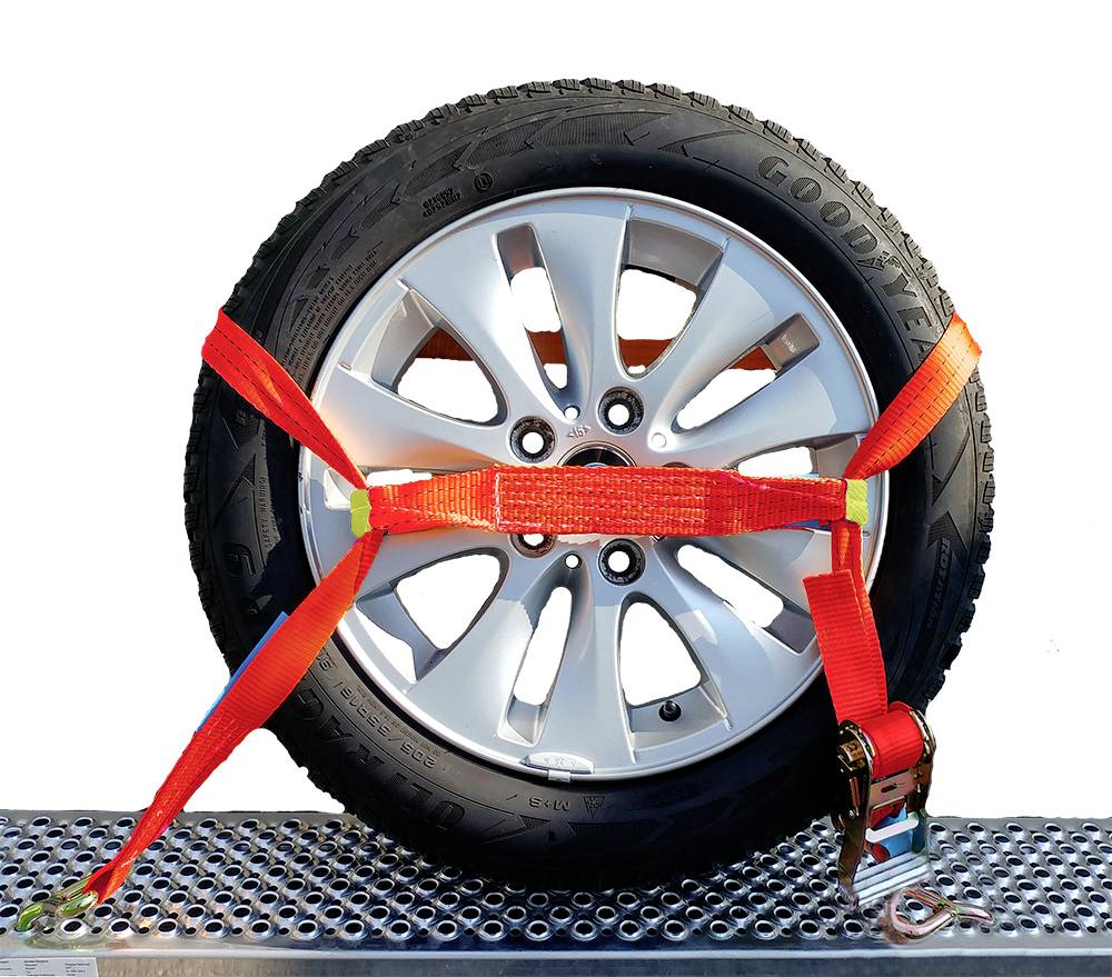 Ein Autoreifen auf einem Metallgitter ist mit einem rot-orangefarbenen Spanngurt gesichert.