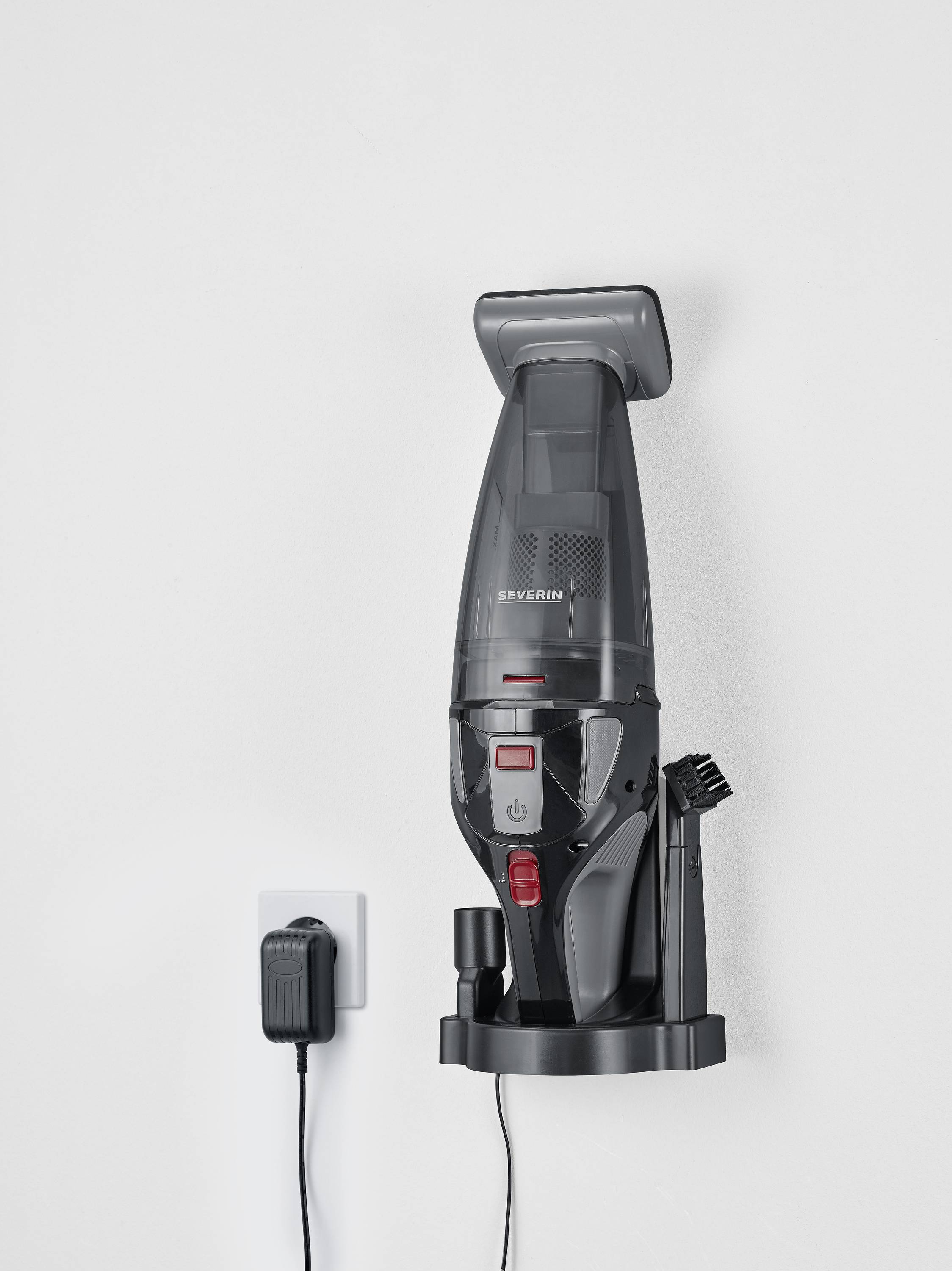 Tragbarer Staubsauger in Ladestation an der Wand. Ladegerät ist an eine Steckdose angeschlossen. Perfekt für einfache Aufbewahrung.