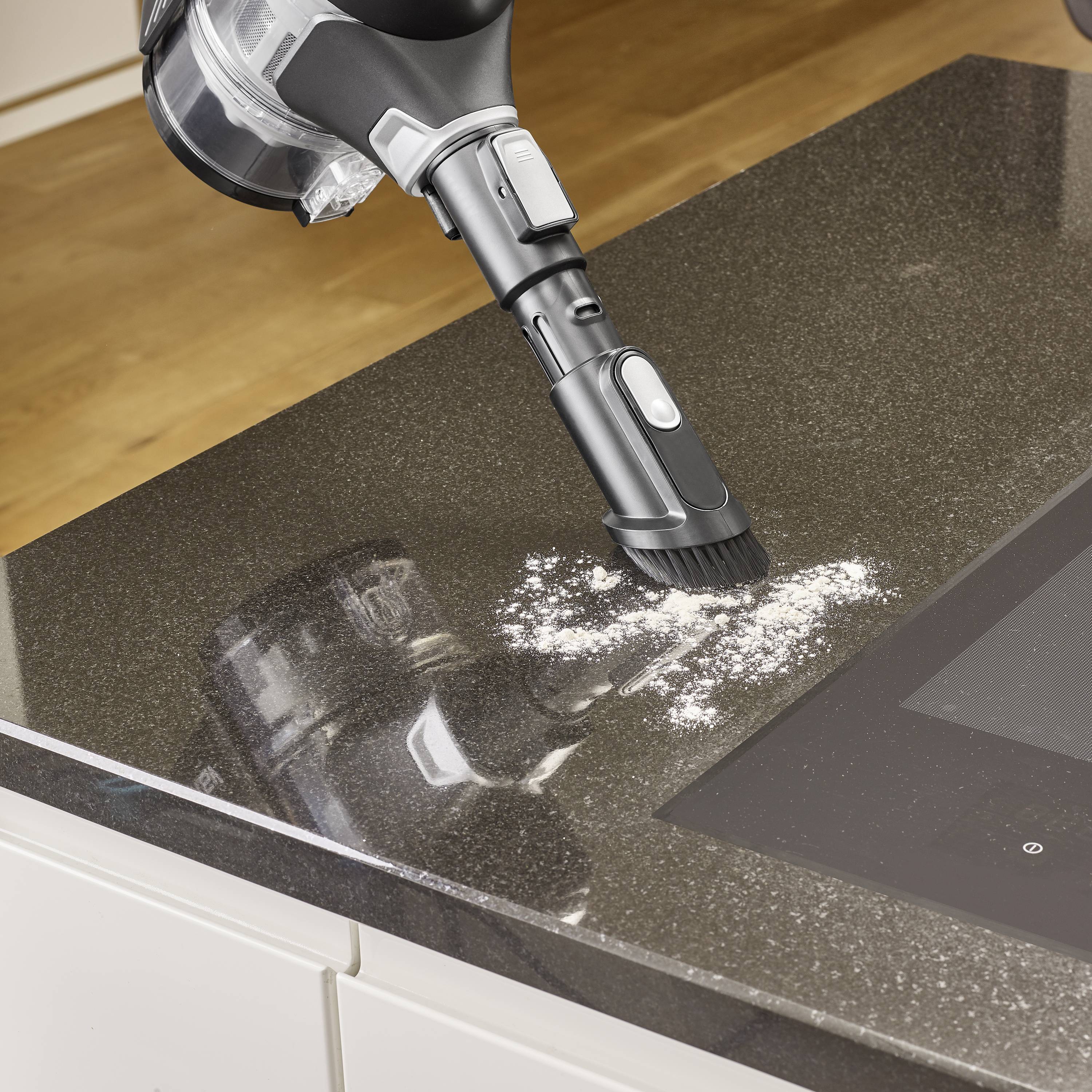 Ein Staubsauger mit einer Bürstendüse saugt Mehl von einer Küchenarbeitsplatte.