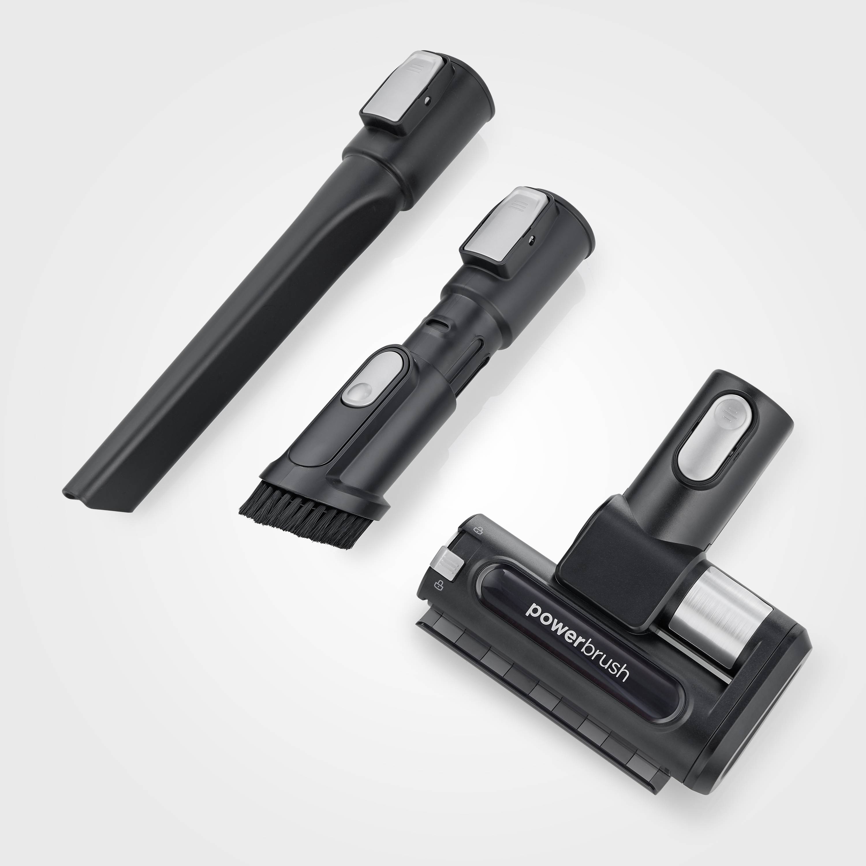Drei schwarze Staubsaugerzubehörteile mit verschiedenen Aufsätzen auf grauem Hintergrund. Darunter eine Bürste mit 'powerbrush'-Aufschrift.