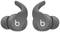 Graue kabellose Ohrhörer mit geschwungenem Design und einem kleinen, aufgedruckten 'b'-Logo. Ideal für den mobilen Musikgenuss.