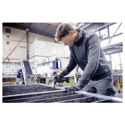 Arbeiter in Schutzbrille und Handschuhen, der einen Metallrahmen in einer Werkstatt oder Fabrik misst oder montiert.