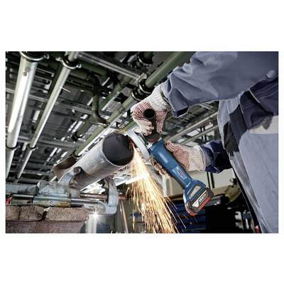 Ein Arbeiter mit Handschuhen verwendet eine Winkelschleifer, um ein Metallrohr zu schneiden, wobei Funken in einer industriellen Umgebung mit Rohren über ihm entstehen.