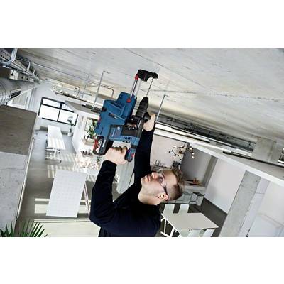 Ein Mann mit Schutzbrille und Gehörschutz bohrt mit einer blauen Bohrmaschine in die Decke eines modernen Büros.