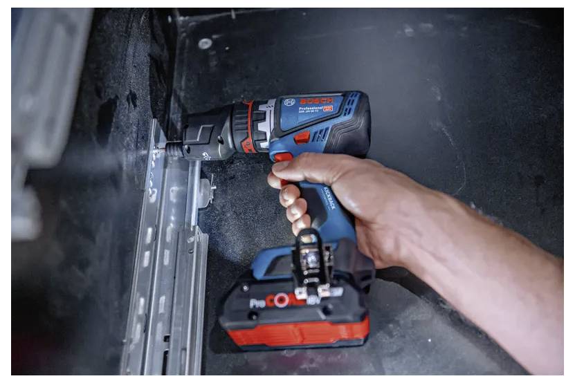 Eine Person verwendet einen Bosch-Akku-Bohrer, um eine Schraube in einem Metallgehäuse anzuziehen und damit ein DIY-Projekt oder eine Hausreparatur durchzuführen.