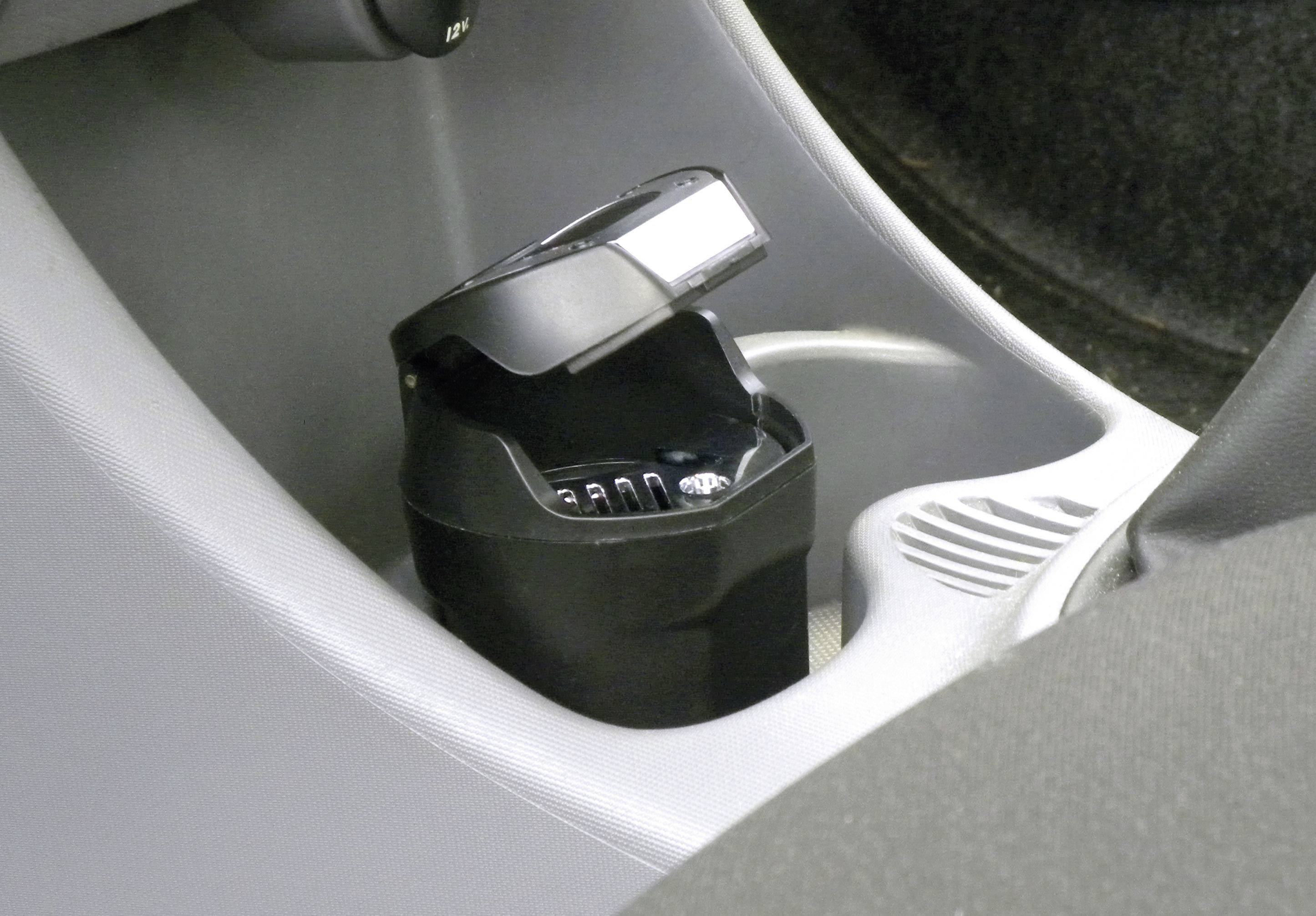 Ein offener Aschenbecher im Getränkehalter eines Autos.