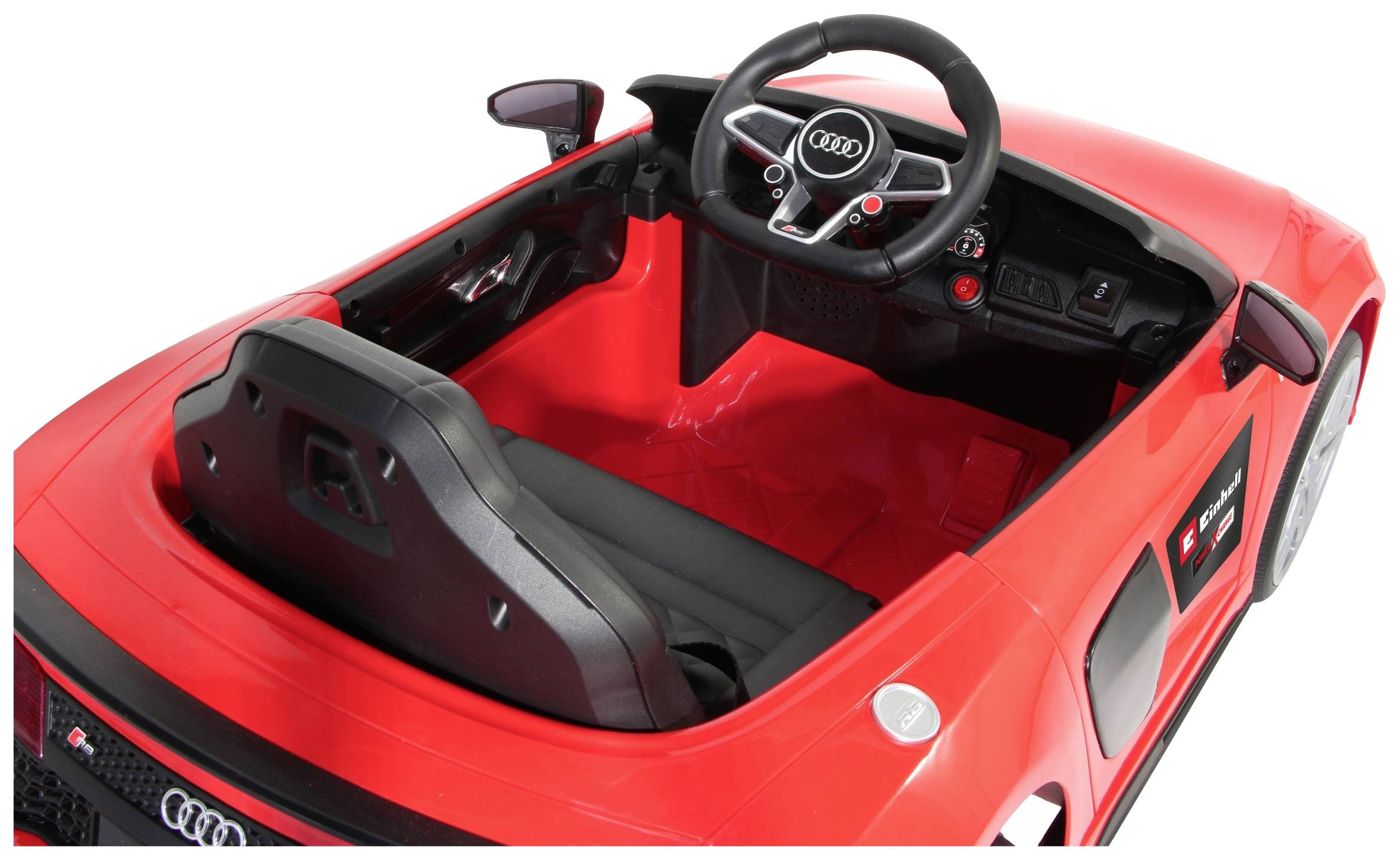 Rotes Spielzeugauto im Cabrio-Stil mit Audi-Logo auf dem Lenkrad. Innenansicht zeigt Sitze und Armaturenbrett.