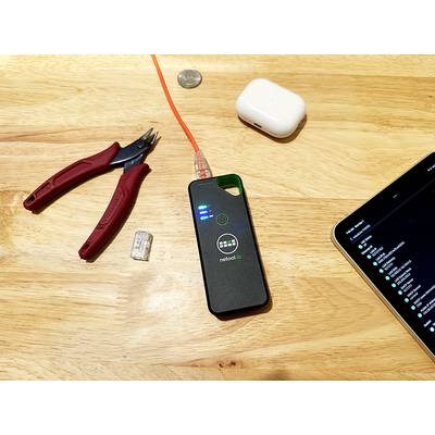 Auf einem Holztisch liegen ein Netzwerktester mit einer eingesteckten orangenen Kabel, daneben AirPods, eine Zange und ein Tablet.