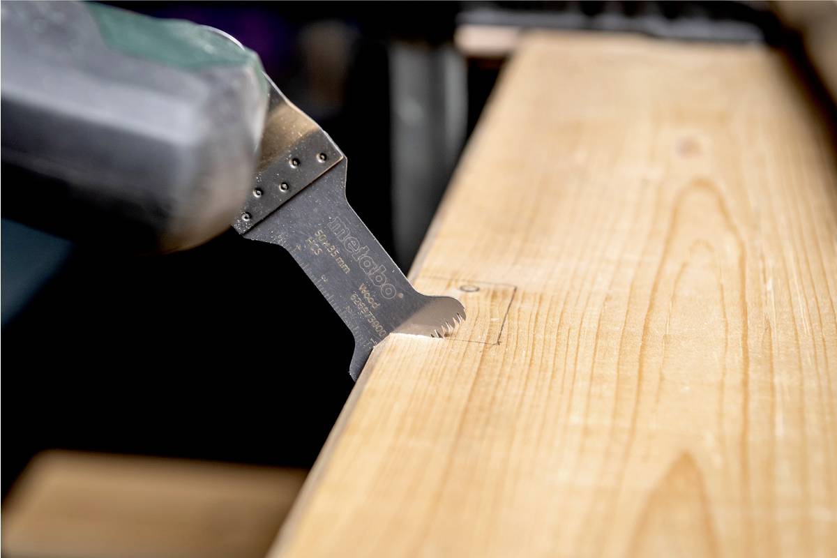 Eine Säge in Nahaufnahme schneidet in ein Holzbrett. Die Zähne der Säge greifen das Holz.