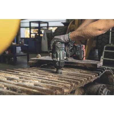 Eine Person verwendet ein elektrisches Werkzeug, um Metallteile auf einer Maschine in einer Werkstatt zu bearbeiten.