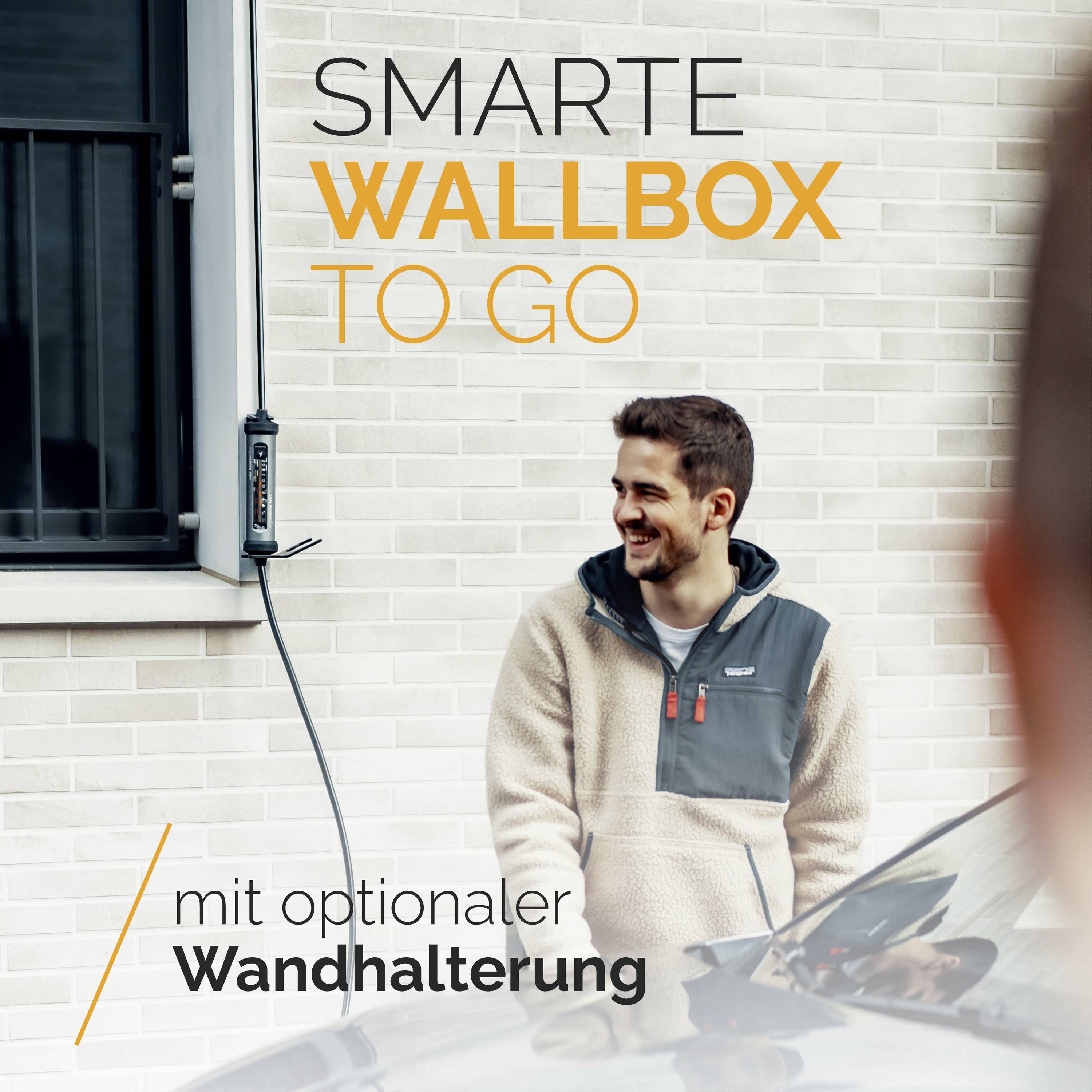 Ein Mann steht neben einer weißen Backsteinwand, lächelt und schaut auf eine montierte Elektroauto-Ladestation mit Kabel. Text: 'Smarte Wallbox to go mit optionaler Wandhalterung'.