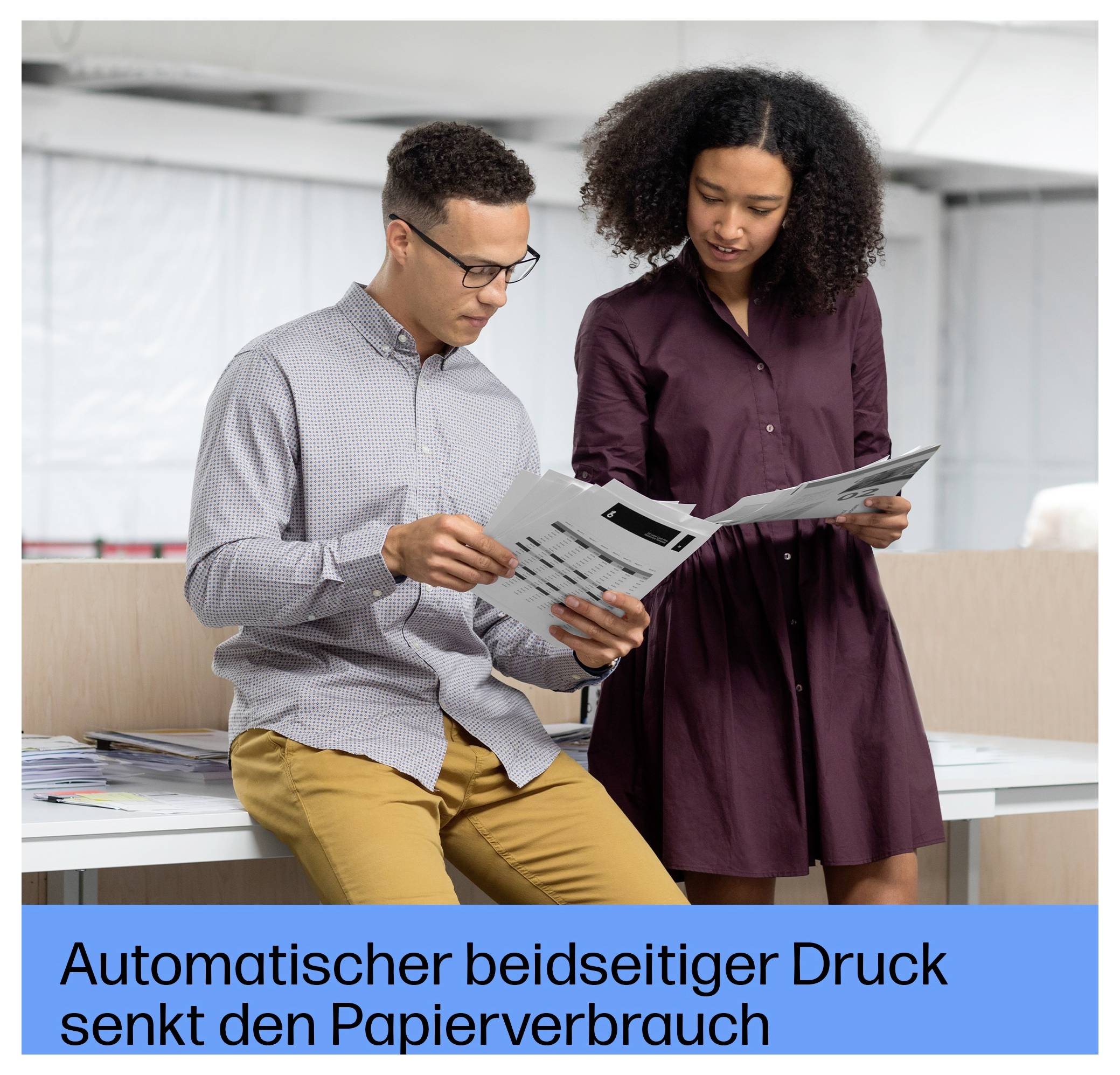 Zwei Kollegen überprüfen gedruckte Dokumente in einem Büro, während ein Banner „Automatischer beidseitiger Druck senkt den Papierverbrauch" liest.