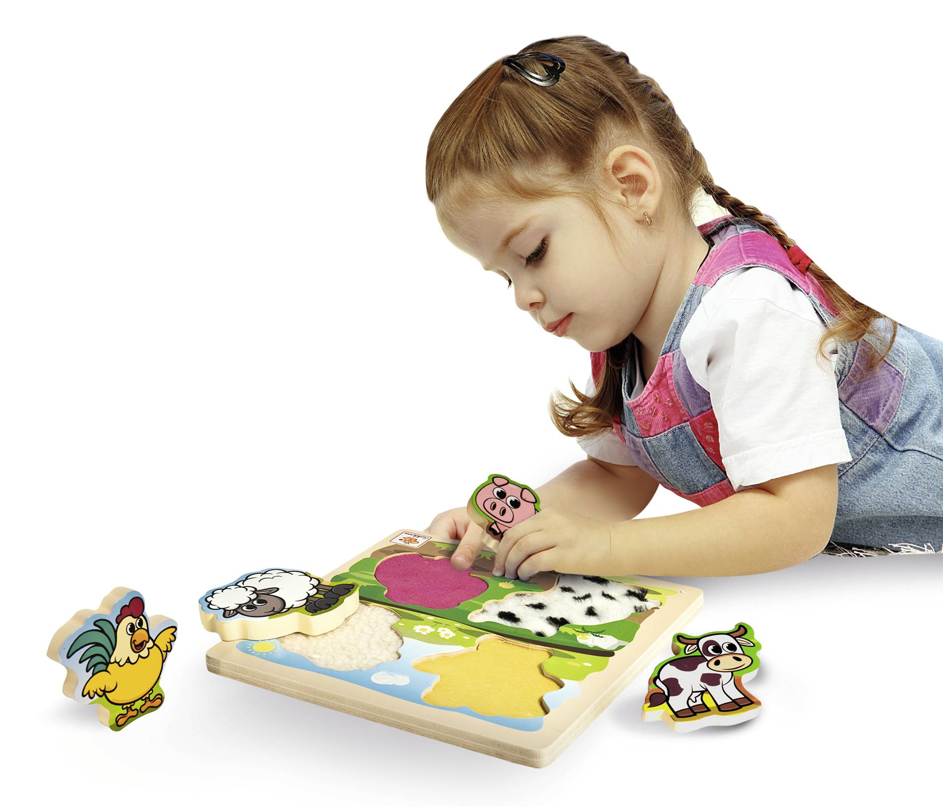 Ein kleines Mädchen spielt mit einem Holzpuzzle, das Tierfiguren zeigt. Sie setzt ein rosa Schweinchen ins Puzzle.