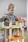 Ein kleiner Junge spielt mit einem bunten Holzbaukasten im Wohnzimmer. Er konzentriert sich auf seine Konstruktion aus Holzteilen.