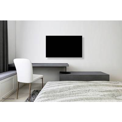 Ein modernes Schlafzimmer mit einem grauen Schreibtisch, einem weißen Stuhl und einem großen Flachbildfernseher an der Wand.