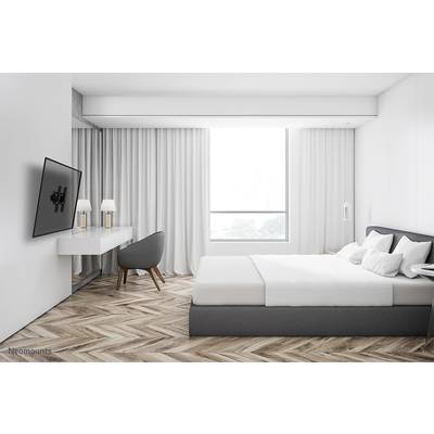 Ein modernes Schlafzimmer mit einem großen Bett, einem Schreibtisch und einem Stuhl. Ein großes Fenster bietet Tageslicht, Vorhänge daneben.