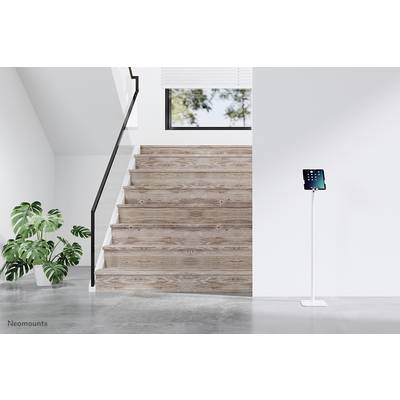 Treppenaufgang aus Holz mit schwarzem Geländer, daneben eine grüne Pflanze. Rechts steht ein Tablet auf einem weißen Ständer.