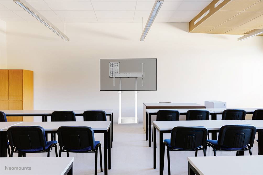 'Klassenzimmer mit Reihen von Tischen und Stühlen, ein großer Bildschirm vorne, Lehrerbereich auf der rechten Seite.'