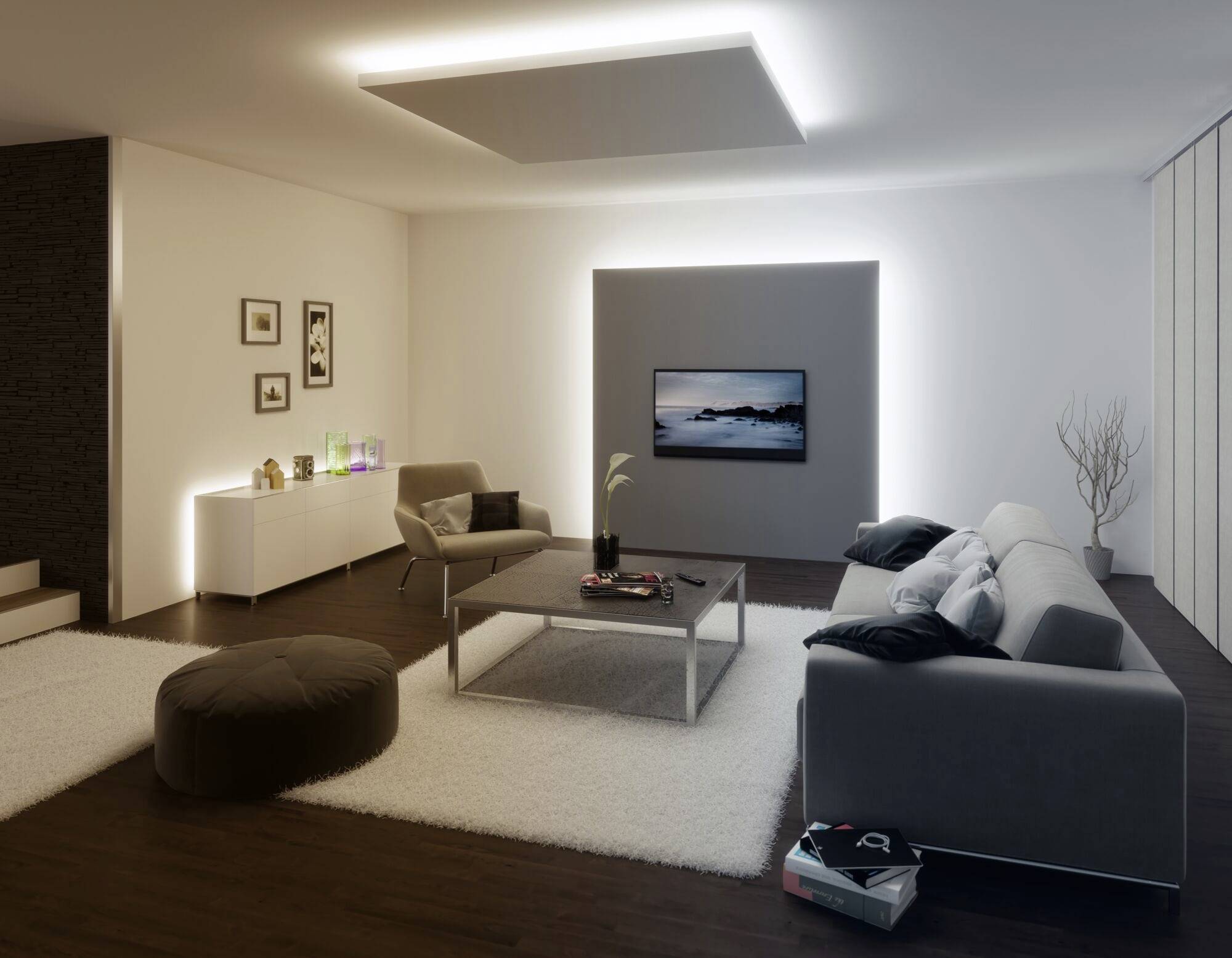 Ein stilvoll eingerichtetes Wohnzimmer mit modernem Sofa, Couchtisch und einem großen Fernseher an der Wand. Dezente Beleuchtung.
