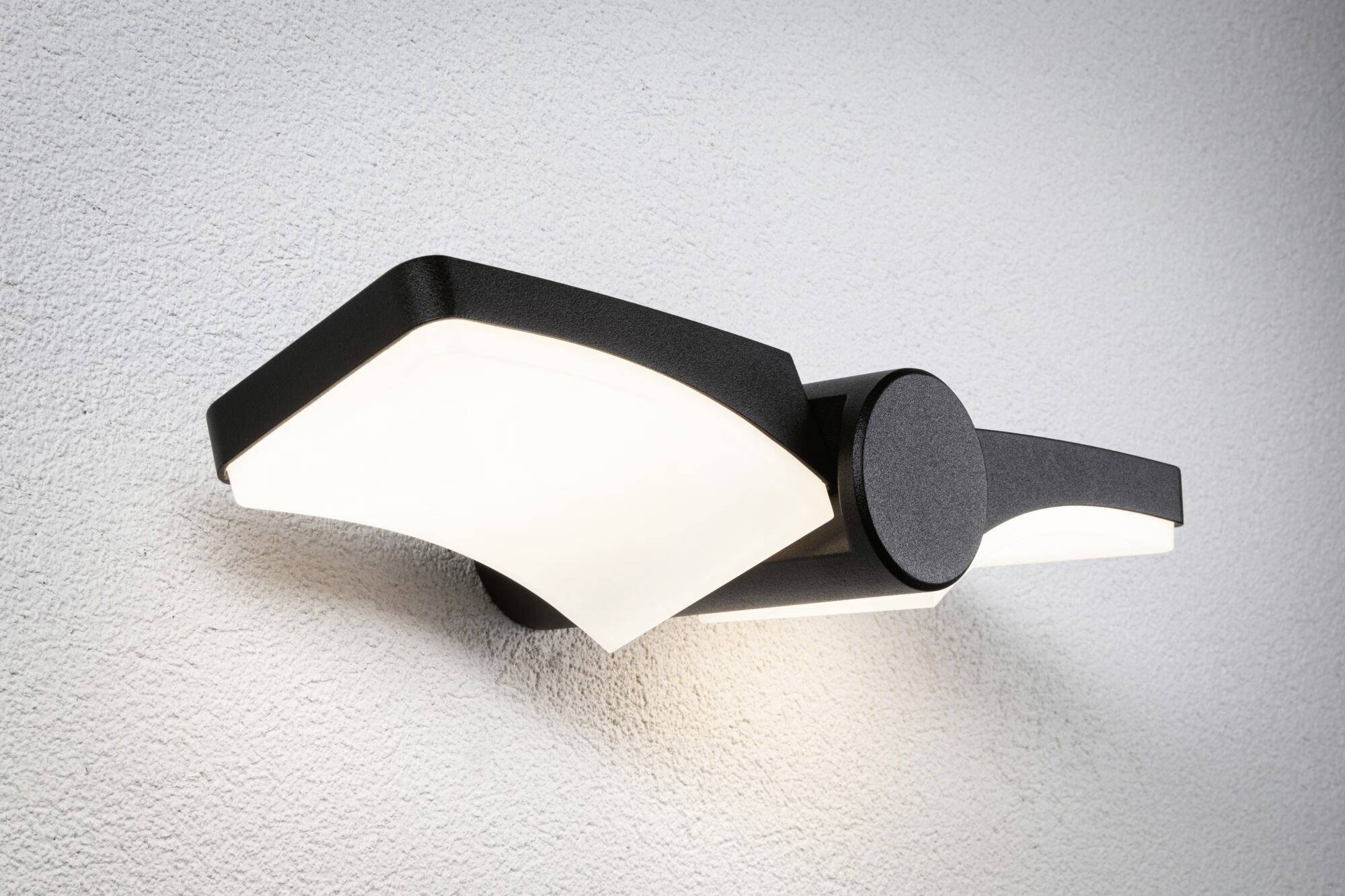 Moderne schwarze Wandleuchte mit gewölbten, rechteckigen Leuchtflächen an einer weißen Wand, strahlt warmes Licht aus.