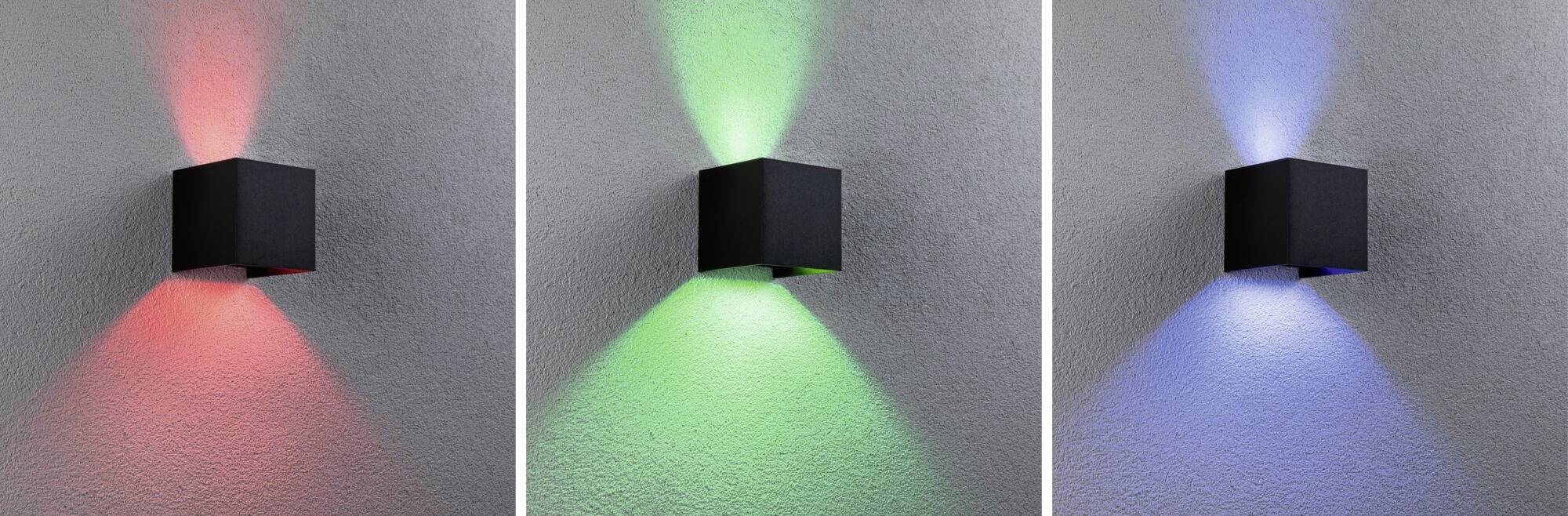 Drei Wandlampen leuchten in Rot, Grün und Blau auf einer grauen Wand. Jede Lampe erzeugt farbiges Licht nach oben und unten.