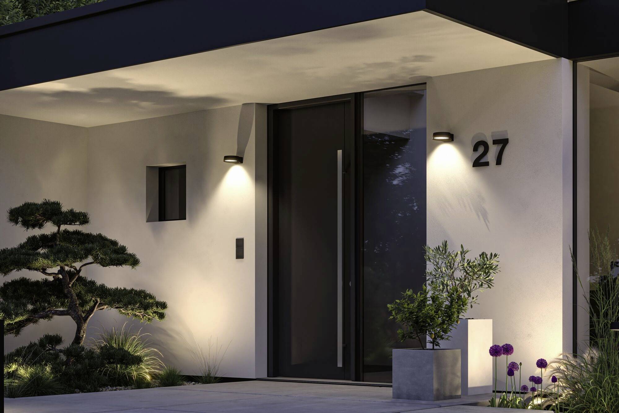 Moderne Hauseingang mit Beleuchtung, Hausnummer 27, seitlich ein kleiner Baum und Pflanzen; wirkt einladend und gepflegt.
