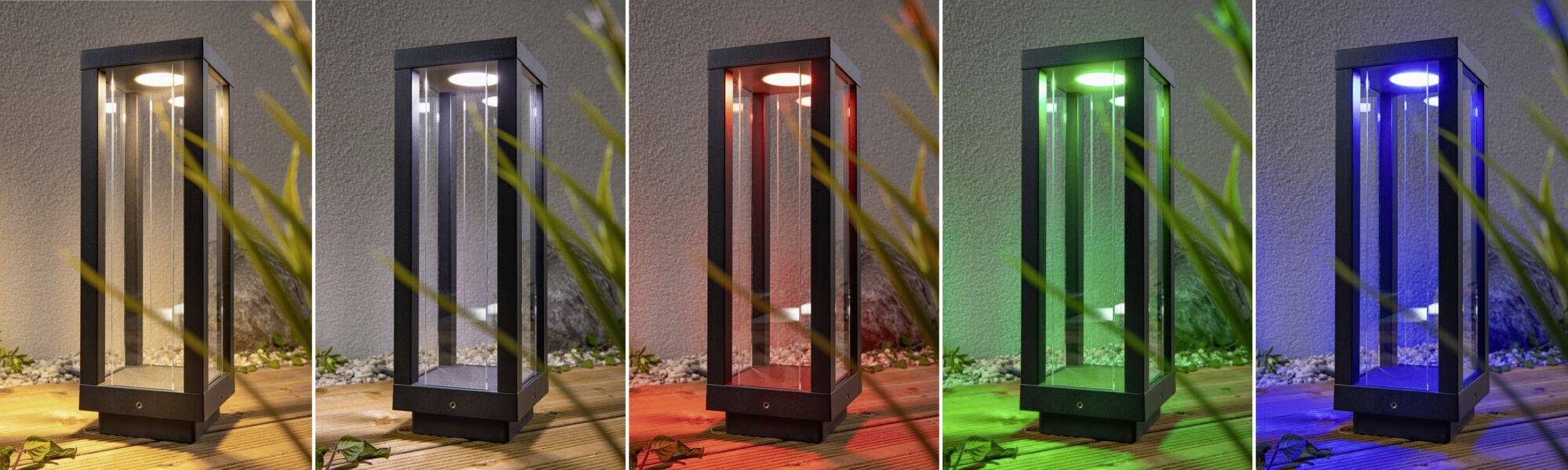 Fünf moderne Außenleuchten in verschiedenen Farben: Weiß, Rot, Grün, Blau und Violett. Die Lampen stehen nebeneinander auf einer Terrasse.