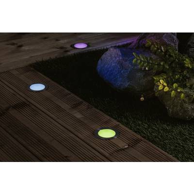 Bunte Bodenlichter auf einer Holzterrasse neben Steinen und Pflanzen, die eine stimmungsvolle Außenbeleuchtung schaffen.