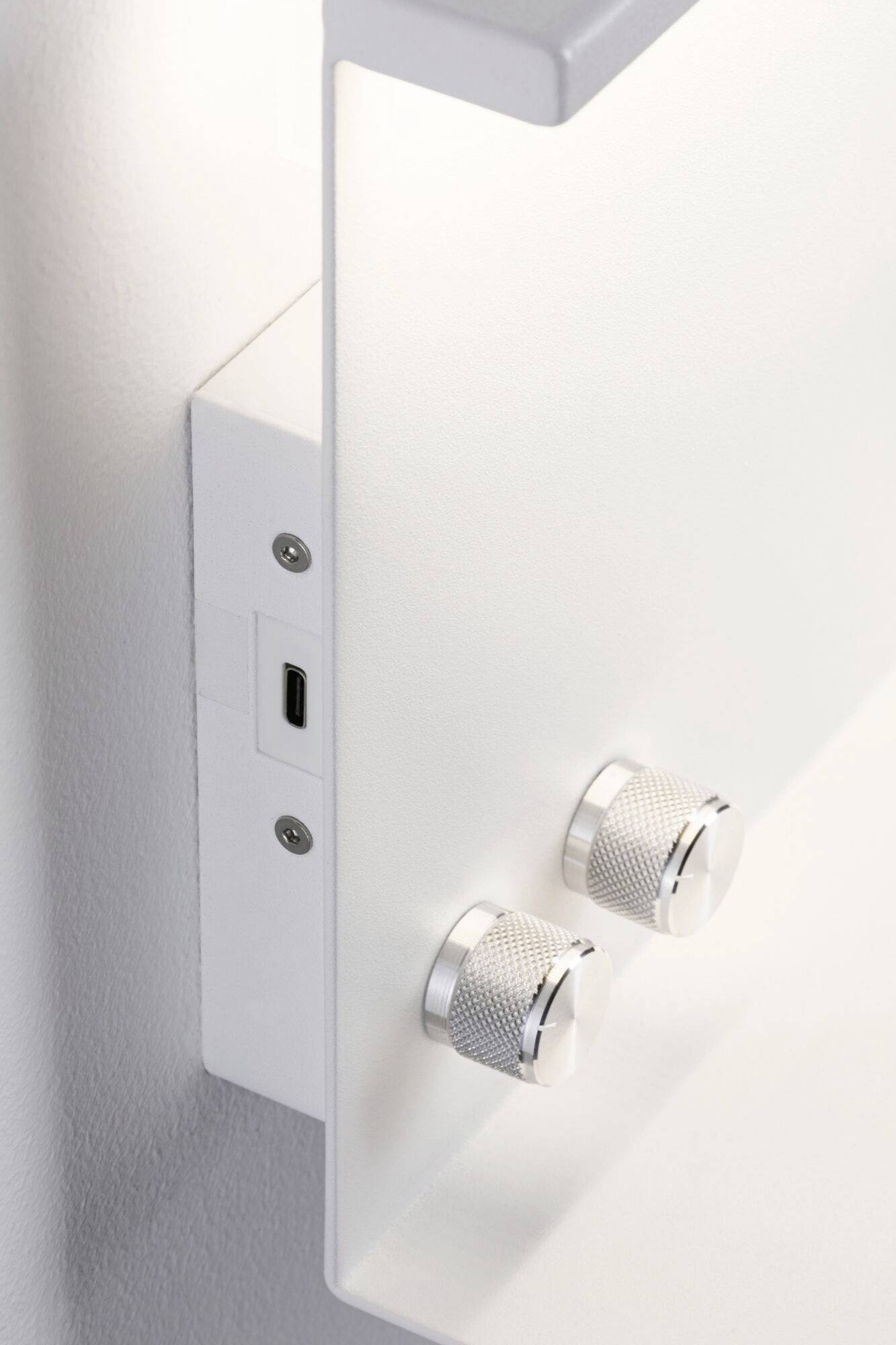 Ein weißes Steuergerät mit zwei silbernen Drehknöpfen an der Wand montiert.