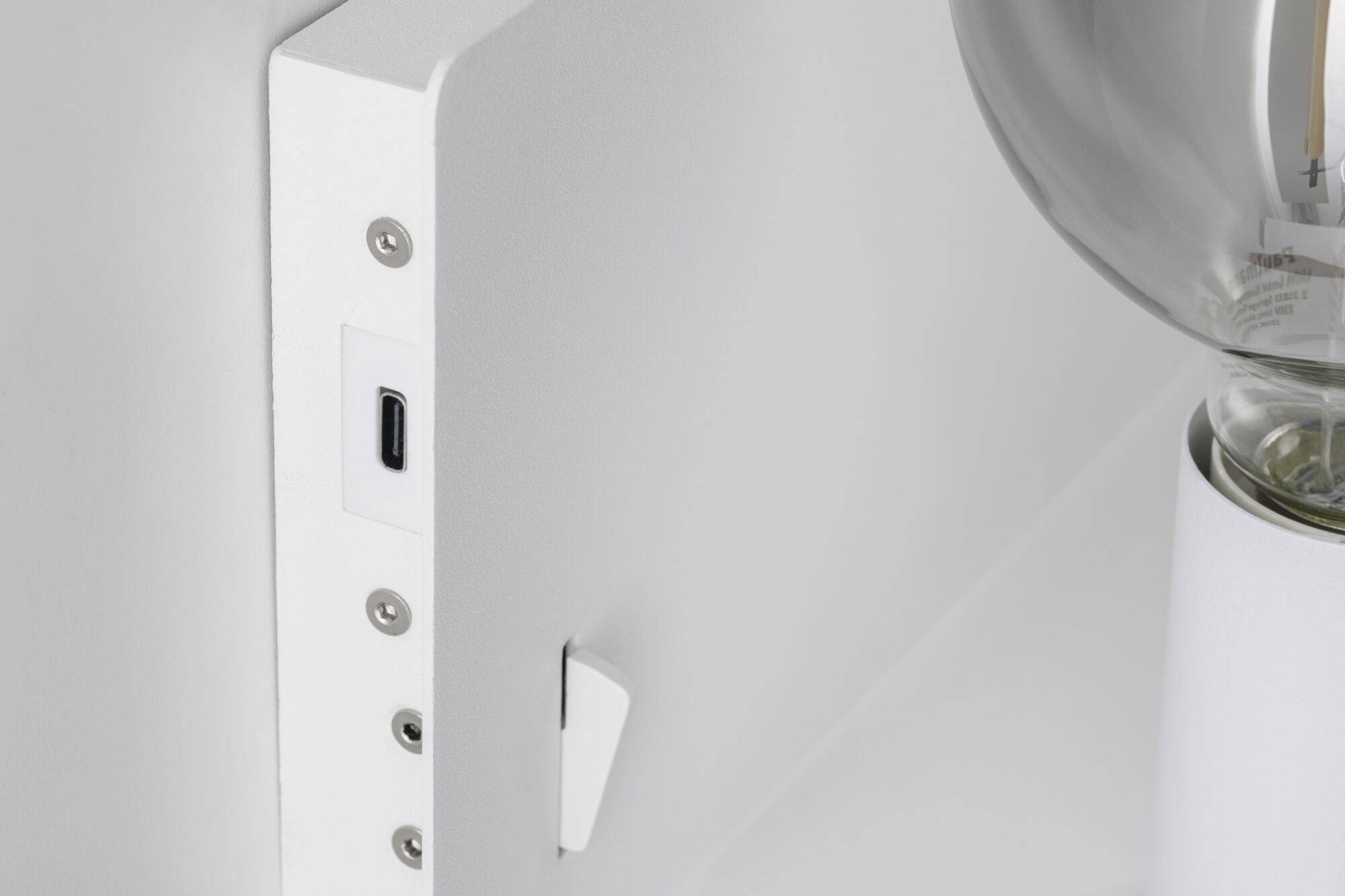 Nahaufnahme eines weißen Geräts mit USB-C-Anschluss und sichtbarer Glühbirne rechts. Technologisches Design sichtbar.