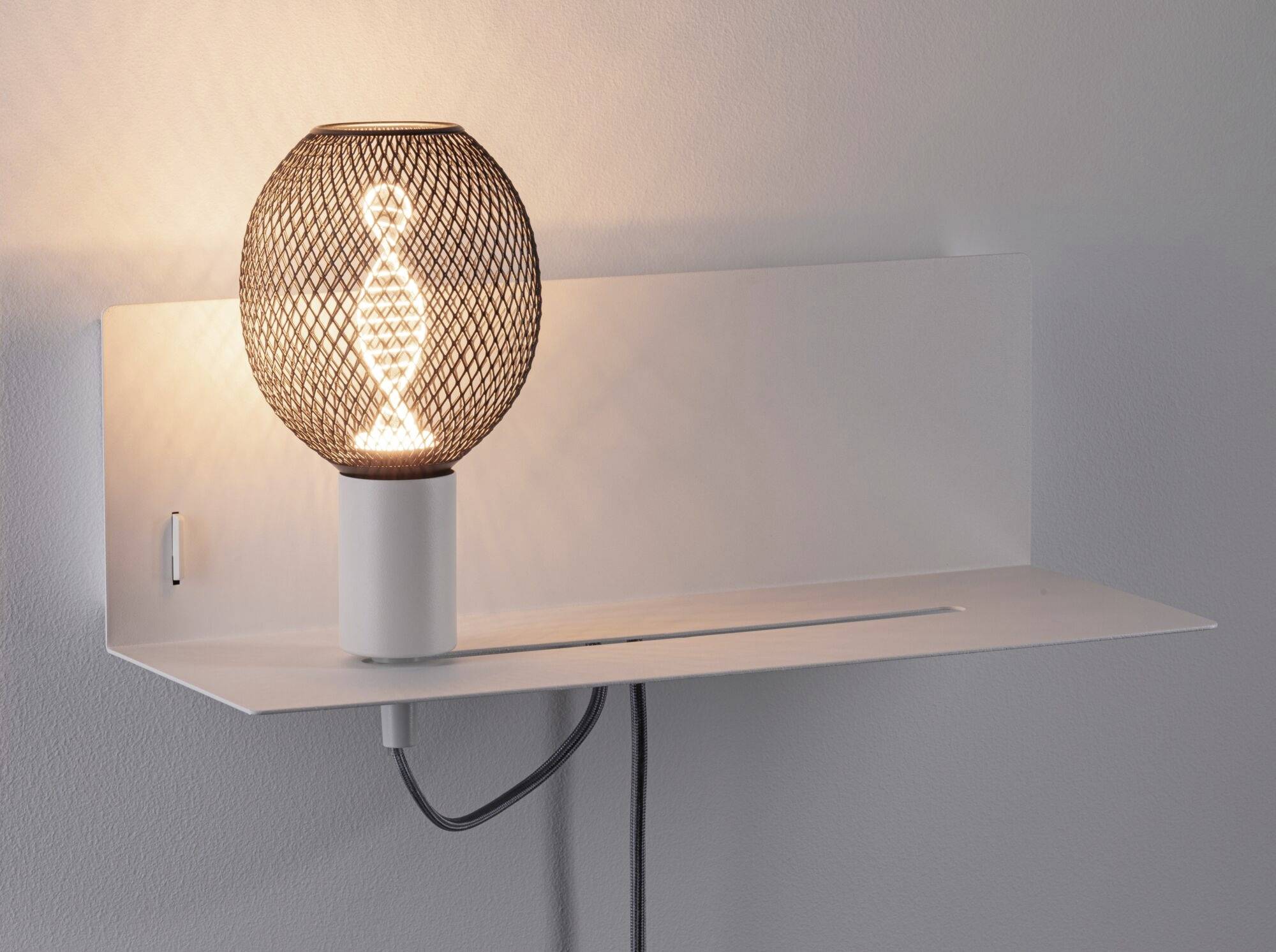 Wandleuchte mit modernem, durchbrochenem Lampenschirm, der Lichtmuster an die Wand wirft.