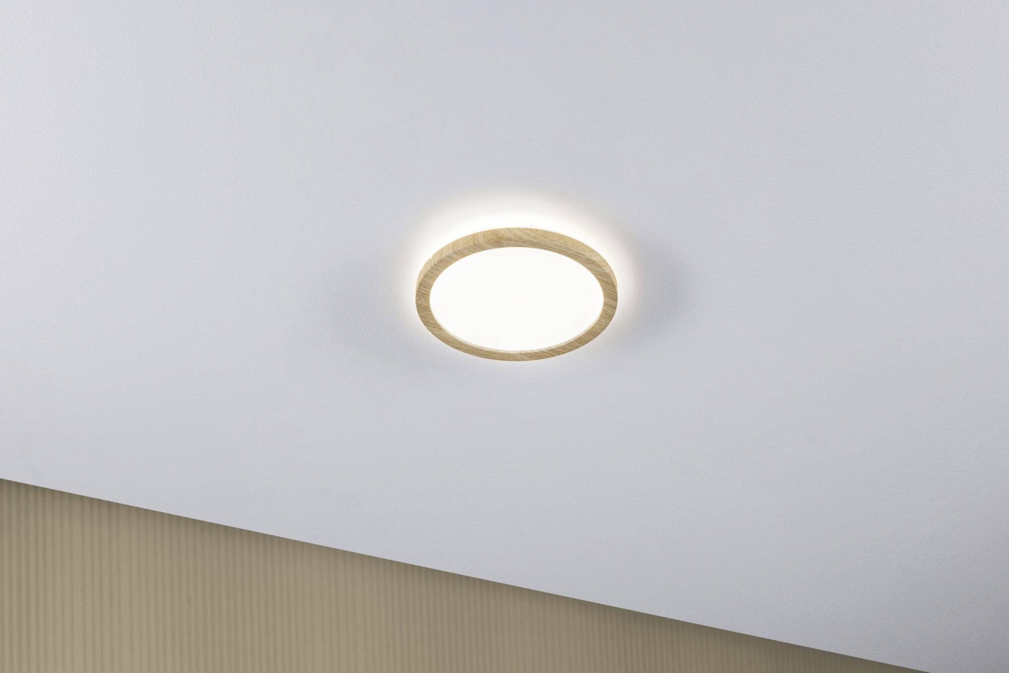 Eine einfache, runde, beleuchtete Deckenlampe in einem Raum mit beiger Tapete.