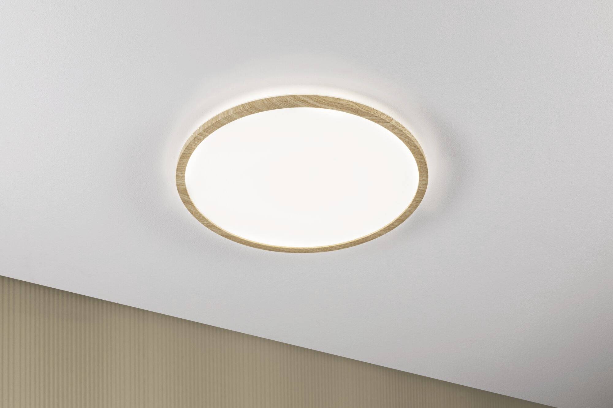 Runde, an der Decke montierte, weiße LED-Leuchte mit holzähnlichem Rand, die sanftes, gleichmäßiges Licht in einem Raum verbreitet.