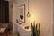 Gemütliches Wohnzimmer im skandinavischen Stil mit Beleuchtung, einem Poster an der Wand, Zimmerpflanze und modernem Regal.