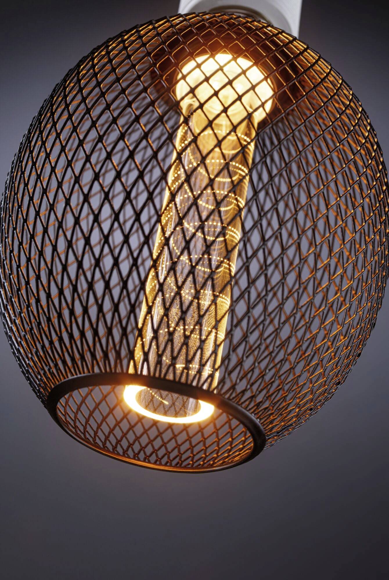 Eine hängende Lampe mit einem rechteckigen, leuchtenden Element, umgeben von einem runden, offenen Metallgitter, strahlt warmes Licht aus.