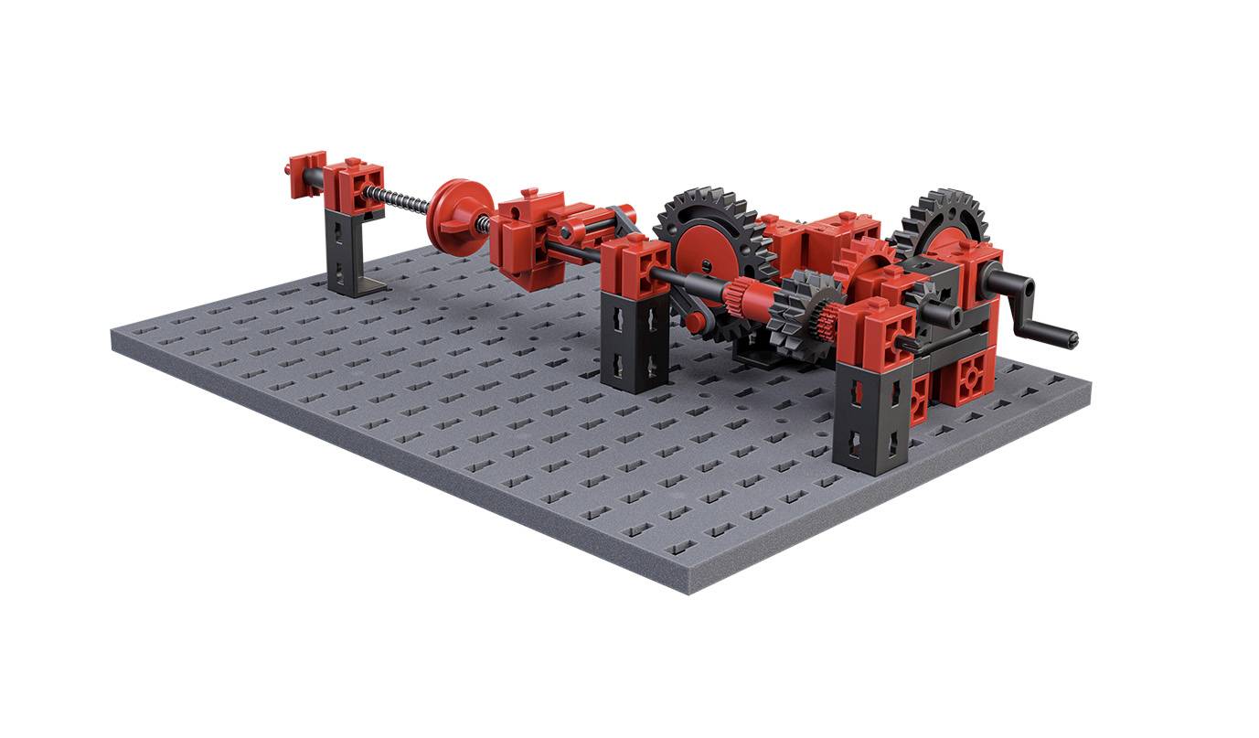 Ein mechanisches Modell aus roten Zahnrädern und Achsen auf einer grauen Basis, das eine komplexe Maschinenstruktur zeigt.