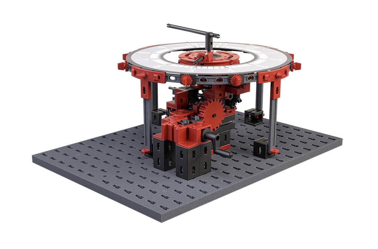 Ein Modell aus Bausteinen zeigt einen Mechanismus mit Zahnrädern auf einer grauen Basis. Rote und schwarze Teile dominieren das Design.