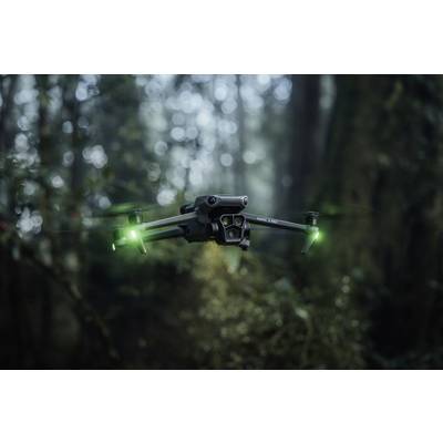 Drohne mit leuchtenden grünen Lichtern schwebt in einem nebligen Wald, umgeben von unscharfen Bäumen.