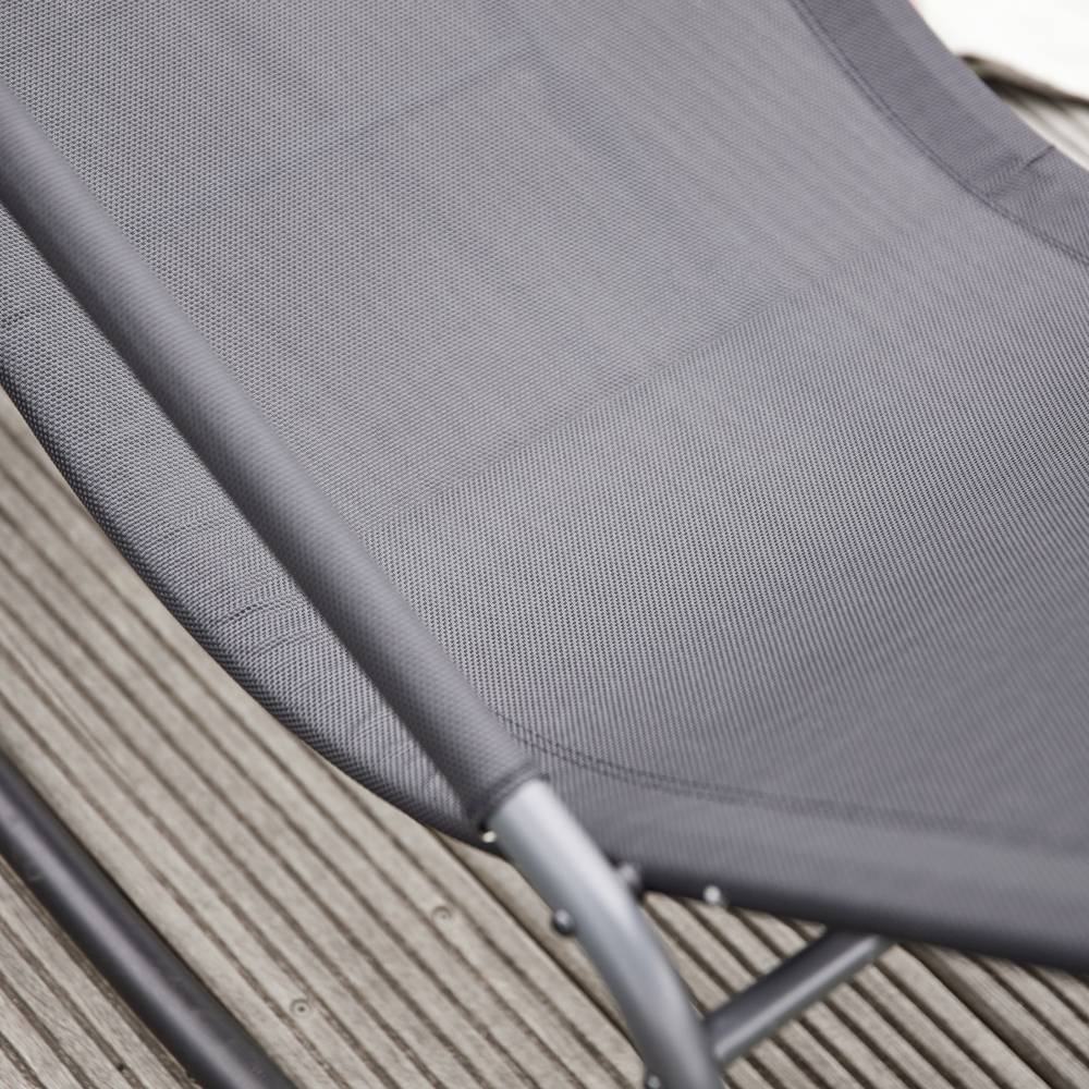 Ein grauer Liegestuhl auf einer Terrasse aus Holzplanken, Teil einer entspannten Außenbereichseinrichtung.