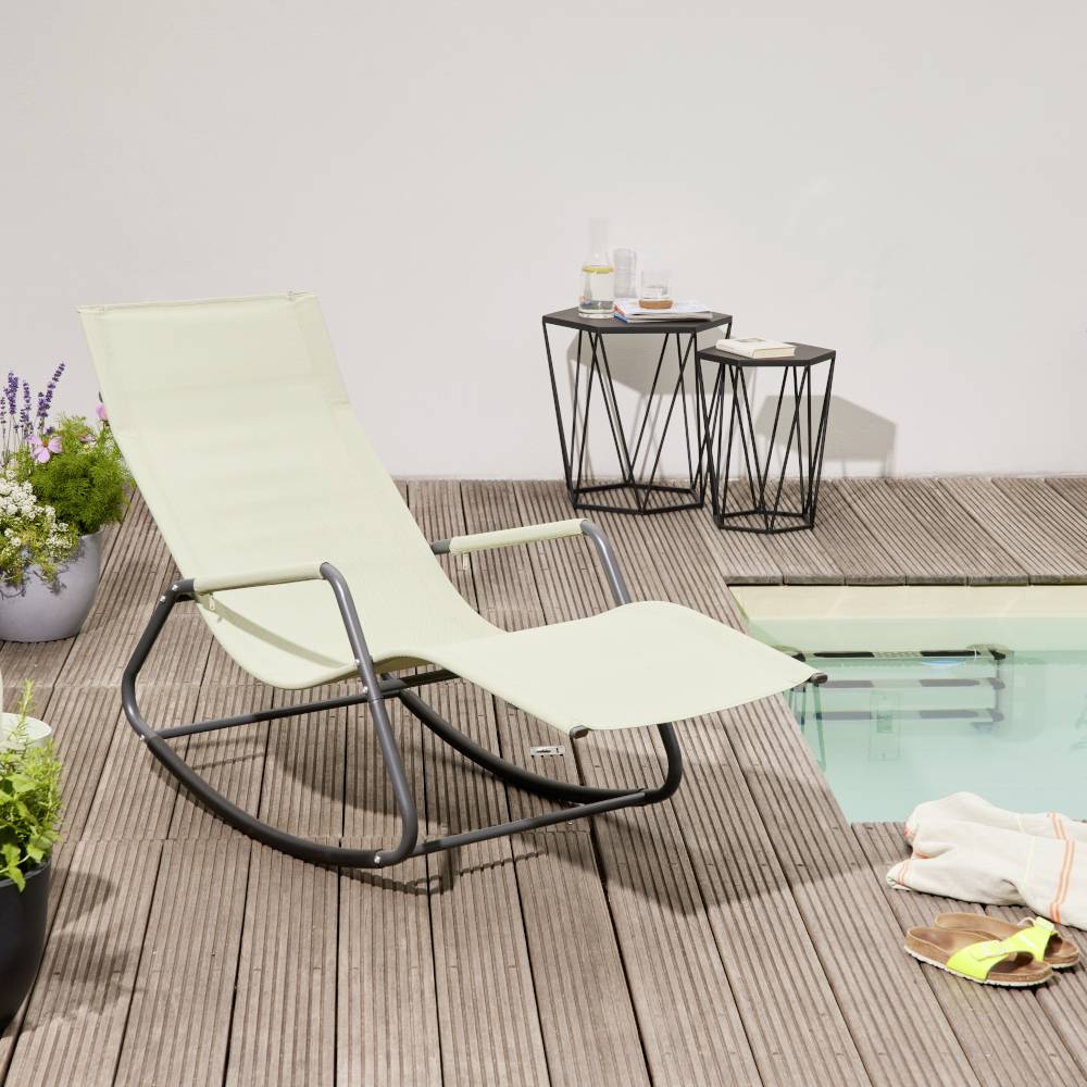 Ein Liegestuhl steht neben einem kleinen Tisch und einem Pool auf einer Holzterrasse. Pflanzen stehen in Töpfen an den Seiten.