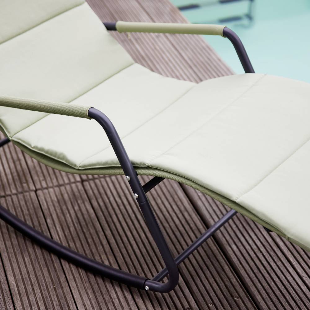 Grüner Liegestuhl auf Holzterrasse am Pool. Entspannungsbereich für Outdoor-Aktivitäten.