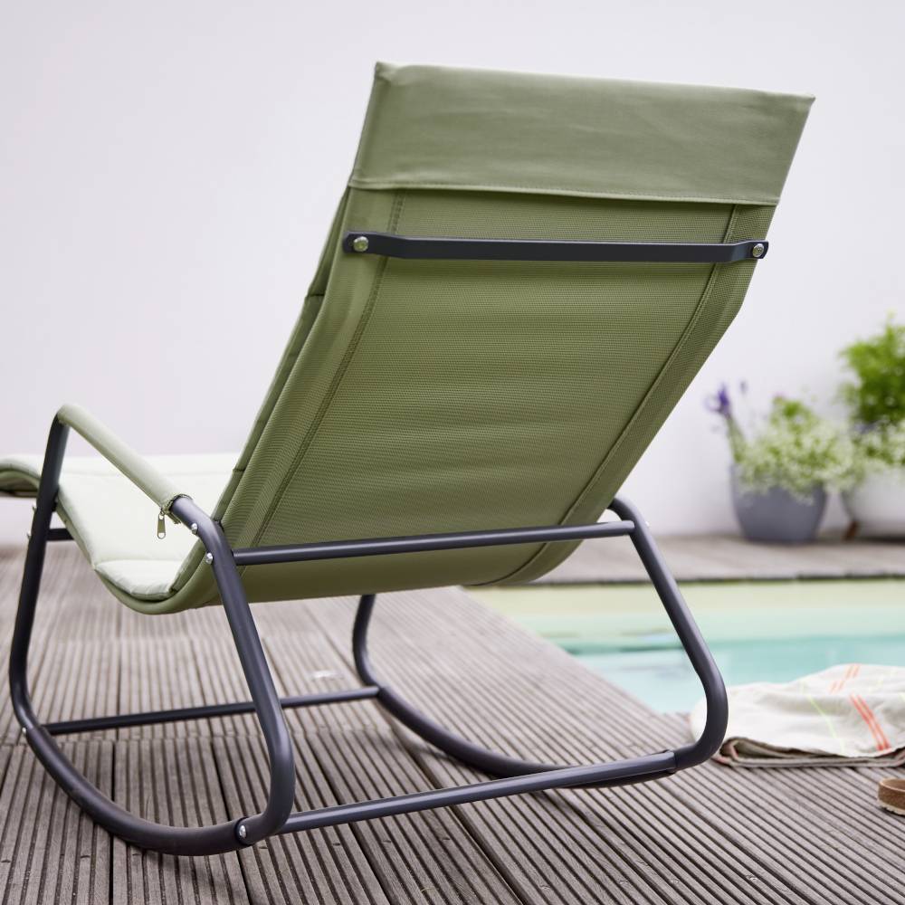 Grüner Liegestuhl mit Metallrahmen steht auf einer Holzterrasse neben einem Pool, Pflanzen im Hintergrund.