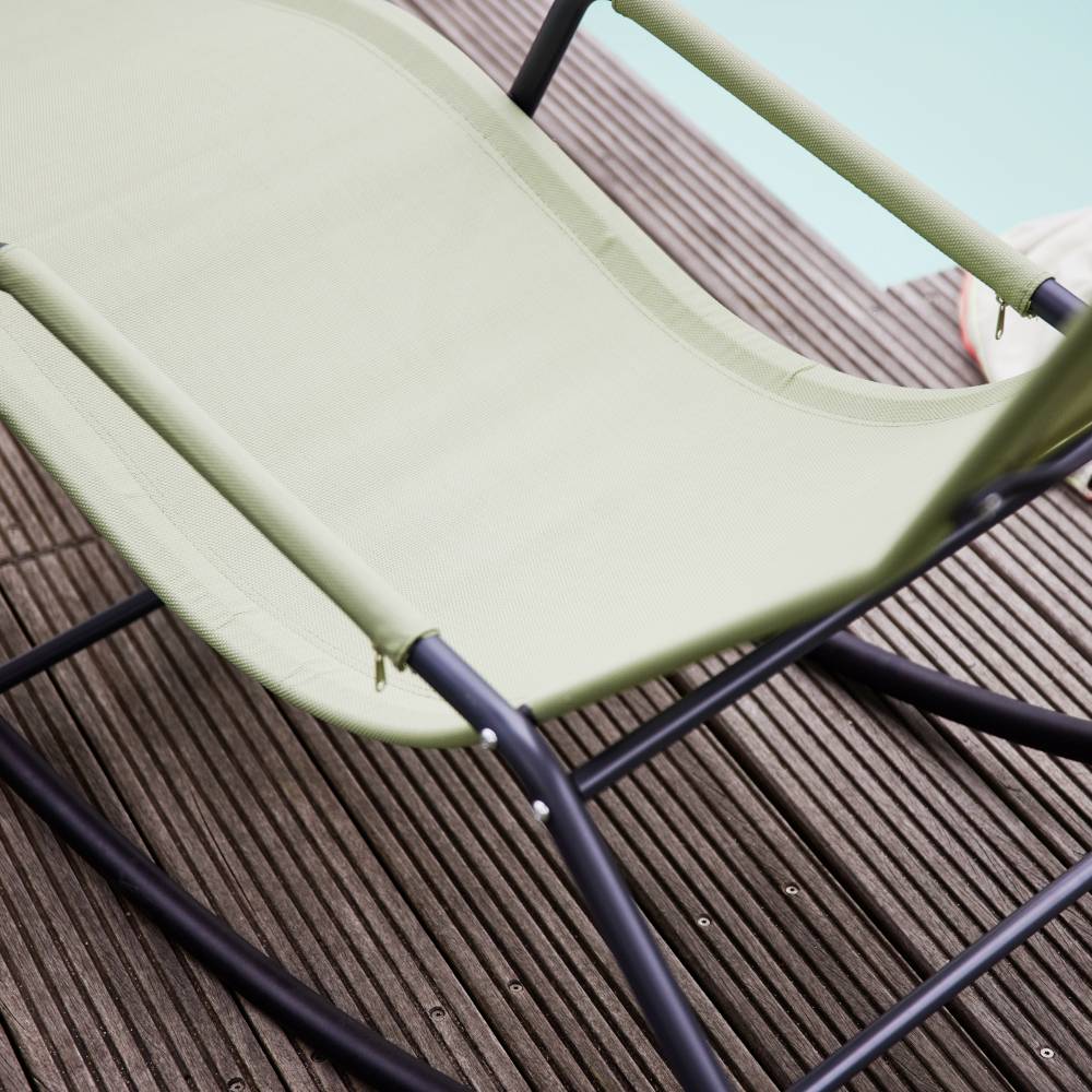 Liegestuhl mit grünem Stoff auf Holzterrasse neben Swimmingpool. Entspannung am Pool bei sonnigem Wetter.