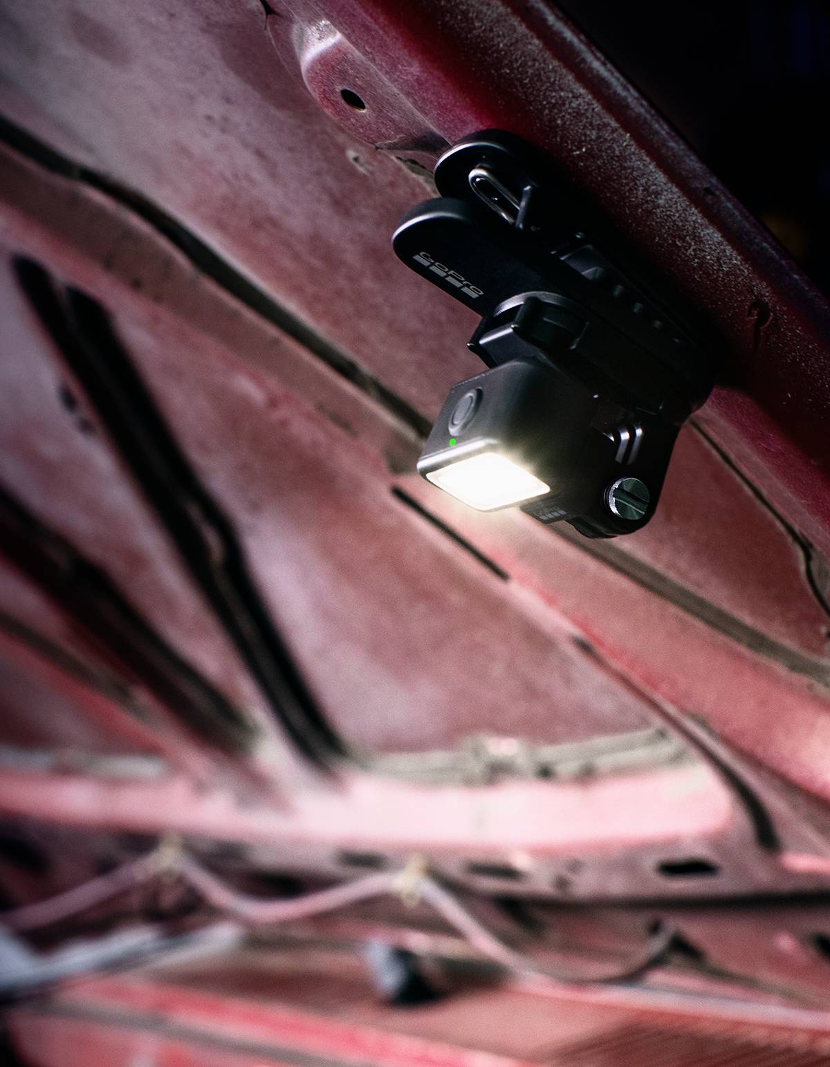 Eine Taschenlampe ist unter einer geöffneten Motorhaube befestigt und beleuchtet den Motorraum.