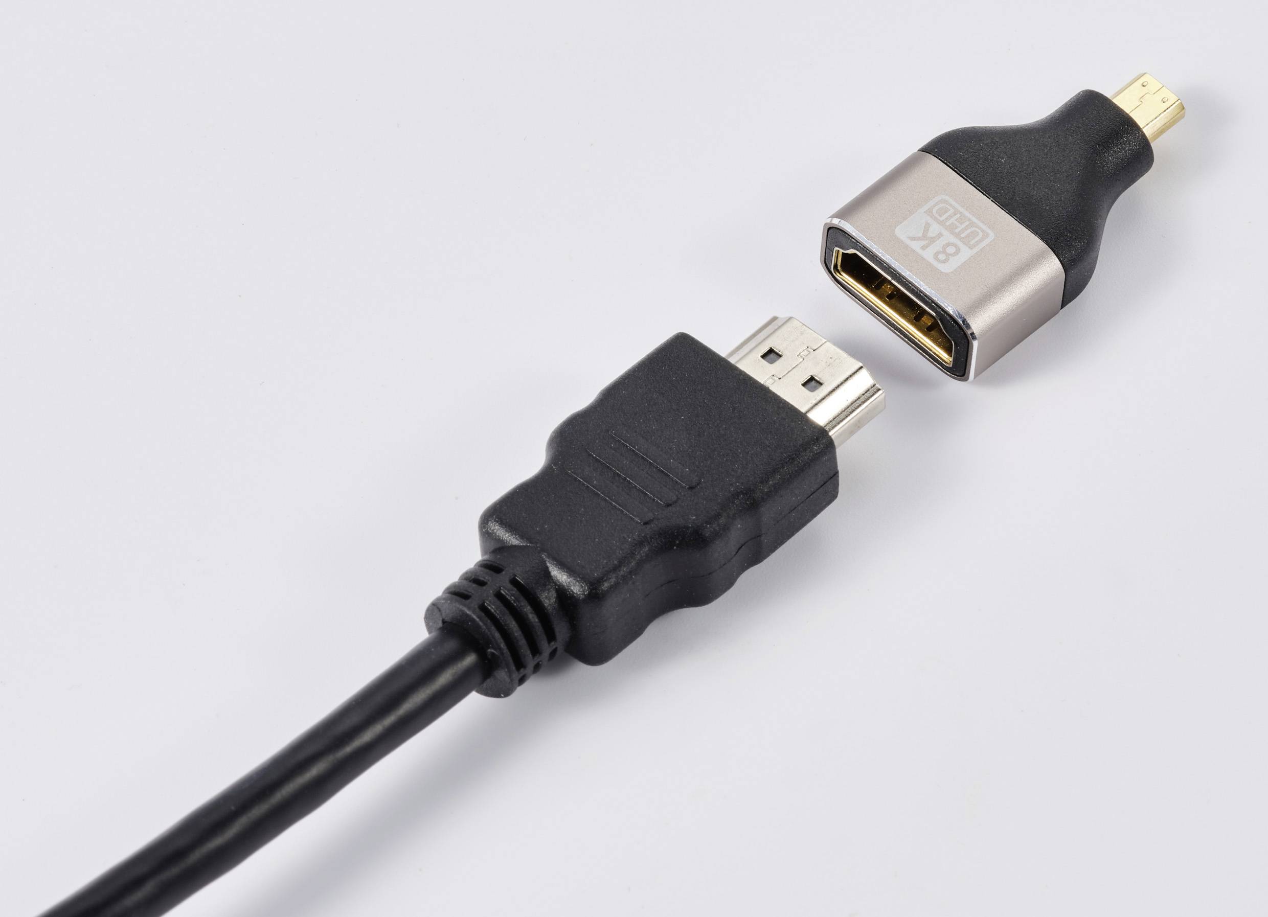 'HDMI-Kabel mit vergoldetem Stecker, getrennt von einem HDMI-Adapter.'